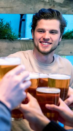 Vrienden proosten lachend met glazen bier 