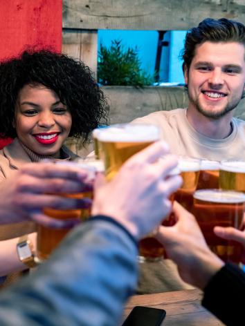 Vrienden proosten lachend met glazen bier 