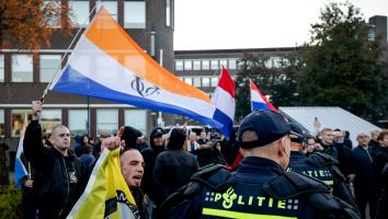 Iemand zwaait met de prinsenvlag bij een anti-azcdemonstratie