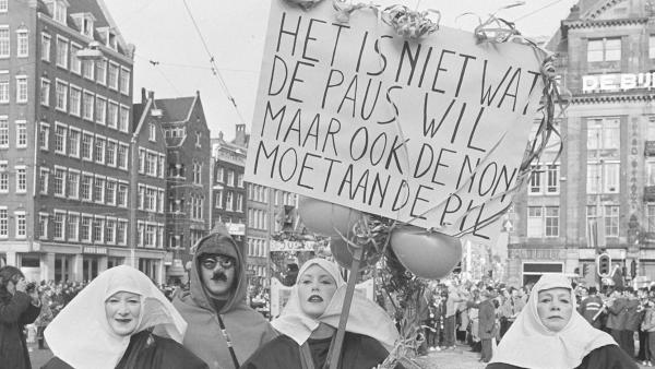Vrouwen gekleed als nonnen lopen mee met protest met bord met de tekst: Het is niet wat de paus wil, maar ook de non moet aan de pil.