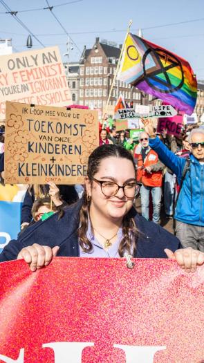 Deelnemers aan de Feminist March lopen door het centrum van Amsterdam met borden en doeken