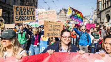 Deelnemers aan de Feminist March lopen door het centrum van Amsterdam met borden en doeken