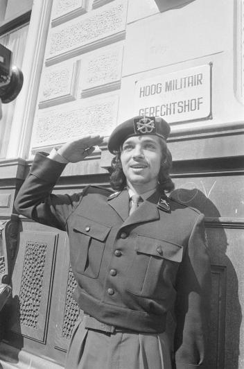 Zwart wit foto van Rinus Wehrmann die met lang haar in uniform salueert