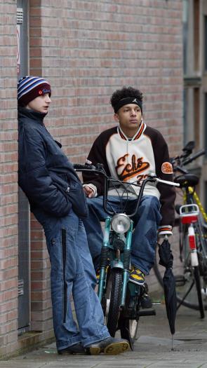 jongeren hangen op de fiets en tegen de muur aan bij hun school in Den Haag