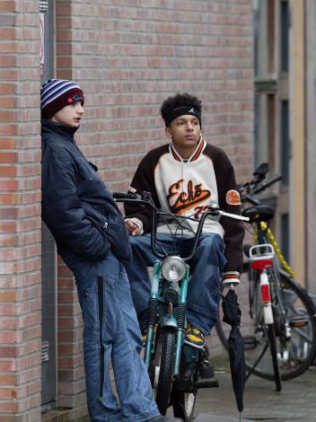 jongeren hangen op de fiets en tegen de muur aan bij hun school in Den Haag