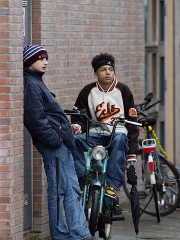 jongeren hangen op de fiets en tegen de muur aan bij hun school in Den Haag