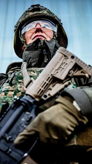 een reservist in legeruniform staat paraat met diens wapen in de hand