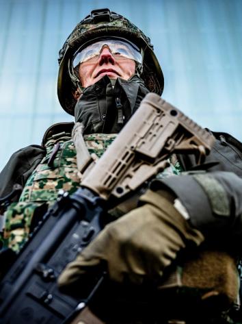 een reservist in legeruniform staat paraat met diens wapen in de hand