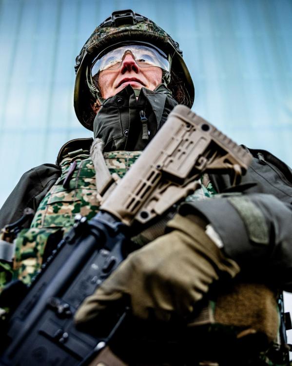een reservist in legeruniform staat paraat met diens wapen in de hand