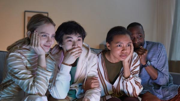 Groep mensen kijkt angstig richting tv