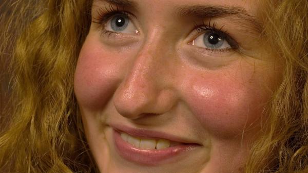 Een close-up van een gezicht van iemand die lacht met hele rode wangen