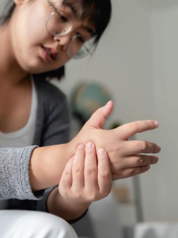 Een vrouw kijkt naar haar hand en drukt met haar andere hand op die hand