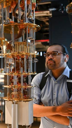 Een werknemer kijkt naar het systeem achter de kwantumcomputer, wat lijkt op een soort metalen toren vooral glanzende metalen deeltjes