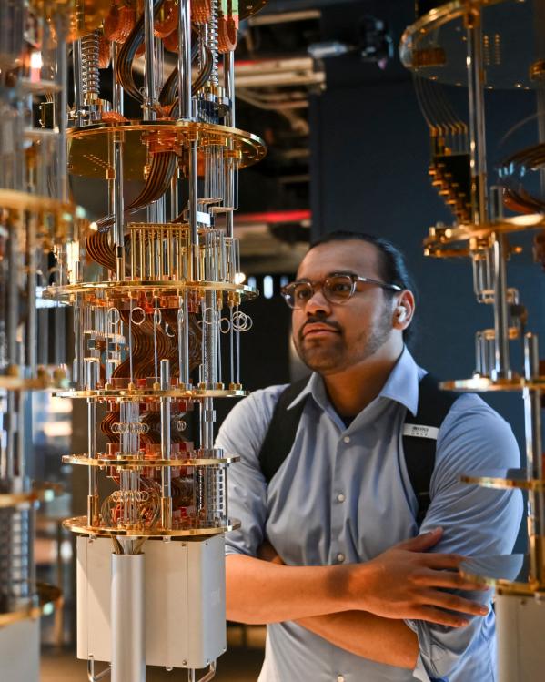 Een werknemer kijkt naar het systeem achter de kwantumcomputer, wat lijkt op een soort metalen toren vooral glanzende metalen deeltjes