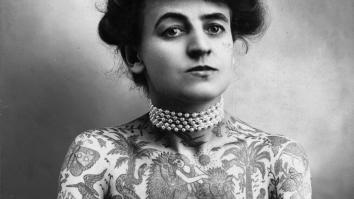 een zwart-witportretfoto van circusartiest Maud Wagner, wiens bovenlichaam vol tattoos zit van allerlei dieren en planten