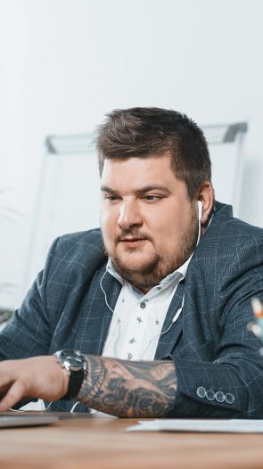 een man met overgewicht zit te werken achter zijn bureau op zijn laptop