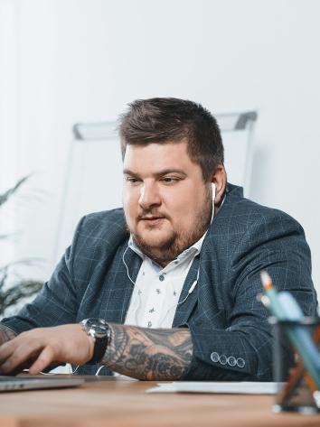 een man met overgewicht zit te werken achter zijn bureau op zijn laptop