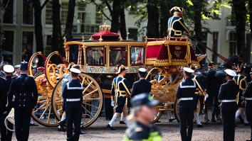 Glazen koets met zwaaiend koningspaar rijdt over straat