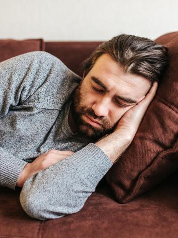 een man ligt op de bank een dutje te doen