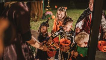 Een groepje kinderen is verkleed voor Halloween en gaat langs de deuren. Ze krijgen snoep van een vrouw die als heks verkleed is.