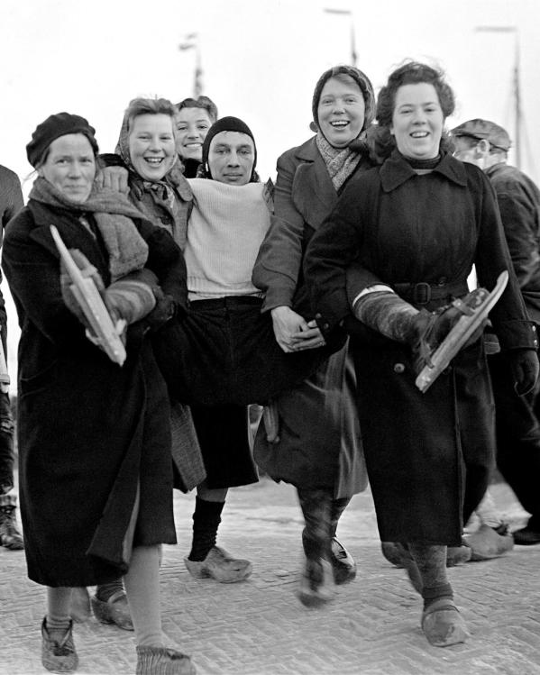 een zwart-witfoto van Friezinnen die een schaatser naar de controlepost dragen